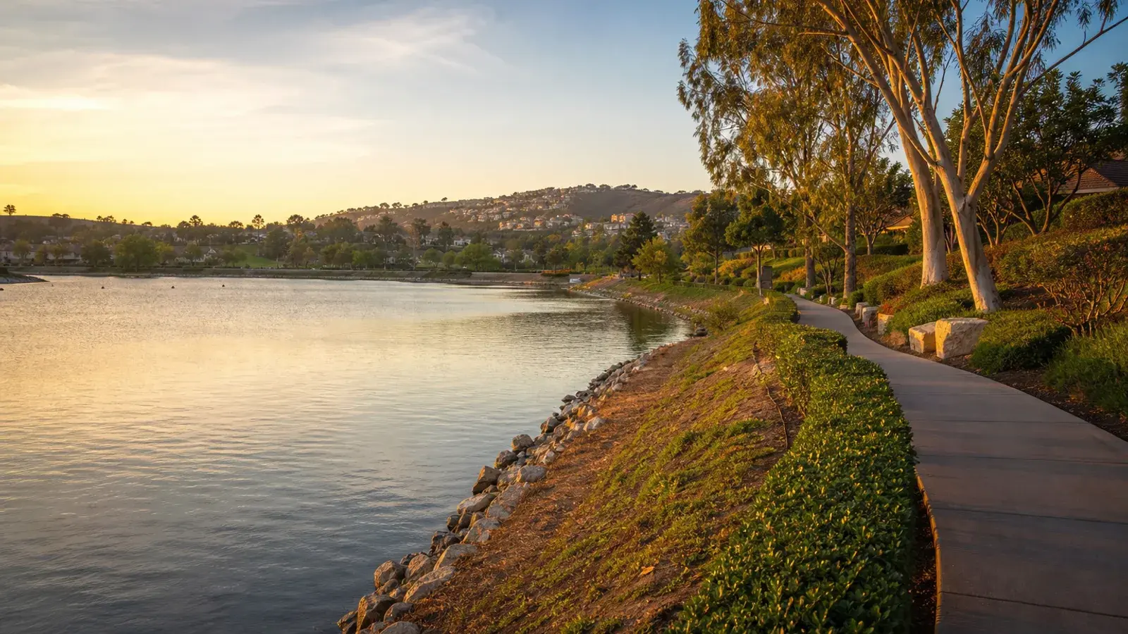Lake Mission Viejo shoreline and tree-lined path at golden hour — HD Liposuction lifestyle Lake Mission Viejo shoreline and tree-lined path at golden hour — HD Liposuction lifestyle | SurgiSculpt®